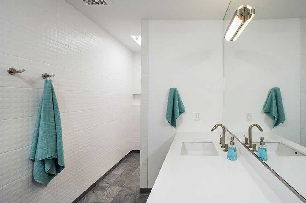 White and gray bathroom with heated floor extending into the shower area.
