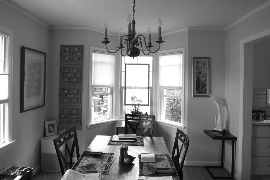 Existing dining room with bay window and small dining table prior to the kitchen remodel.