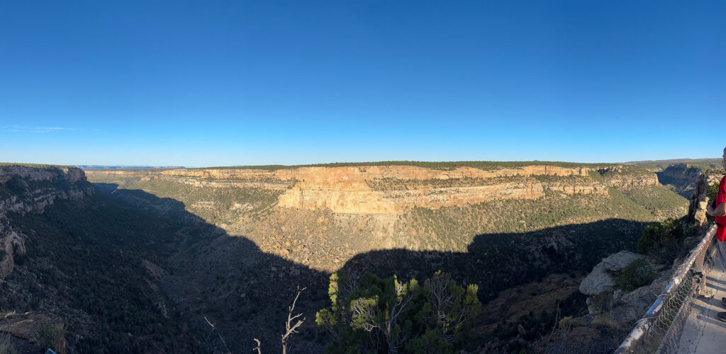 Wide canyon view at Mesa Verde National Park from an overlook, showing the scale of the landscape and distant cliff walls.