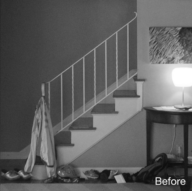 Before renovation entry hall with a simple stair, painted railing, and cluttered floor area.