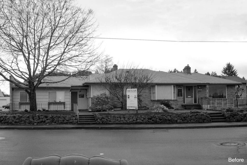 Black and white photo of an existing single-story commercial building with multiple entrances, low rooflines, and minimal street presence along a residential street.