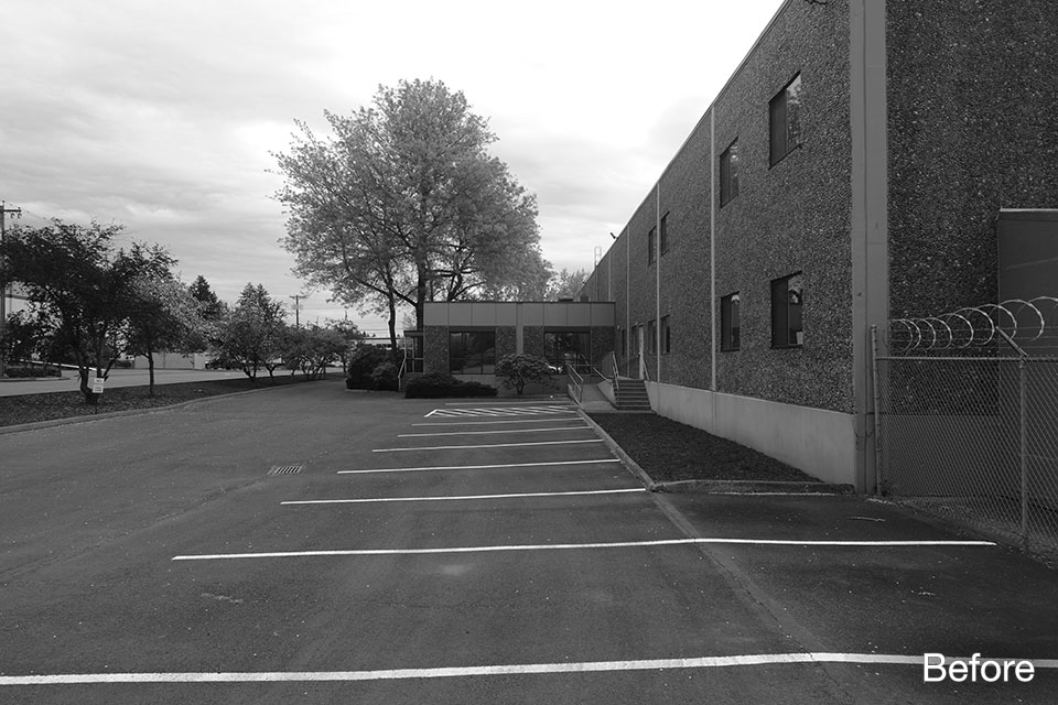 Before photo of commercial building showing existing entry, parking lot with striped spaces, and blank façade along the street.